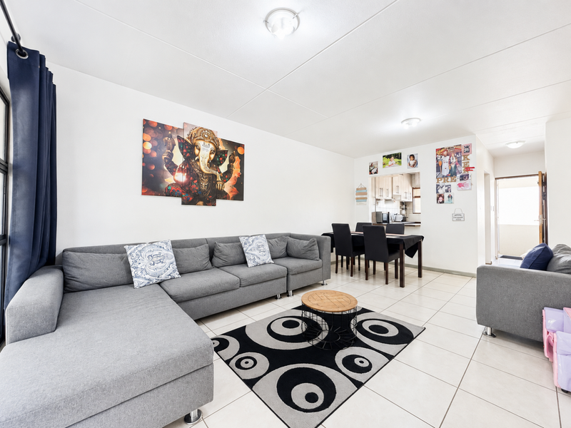 Open-plan living and dining area featuring neutral tiled flooring, clean white walls, and a convenient pass-through opening to the kitchen.