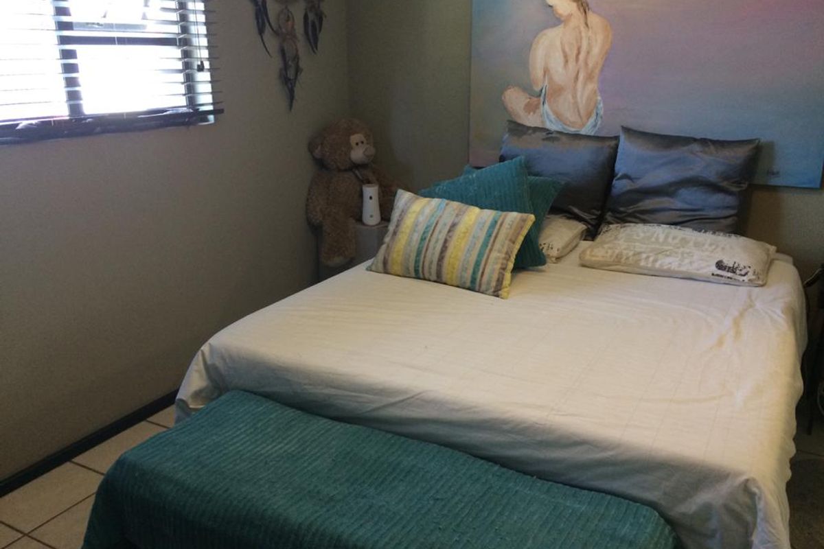 A bedroom featuring tiled flooring and a window with fitted blinds.