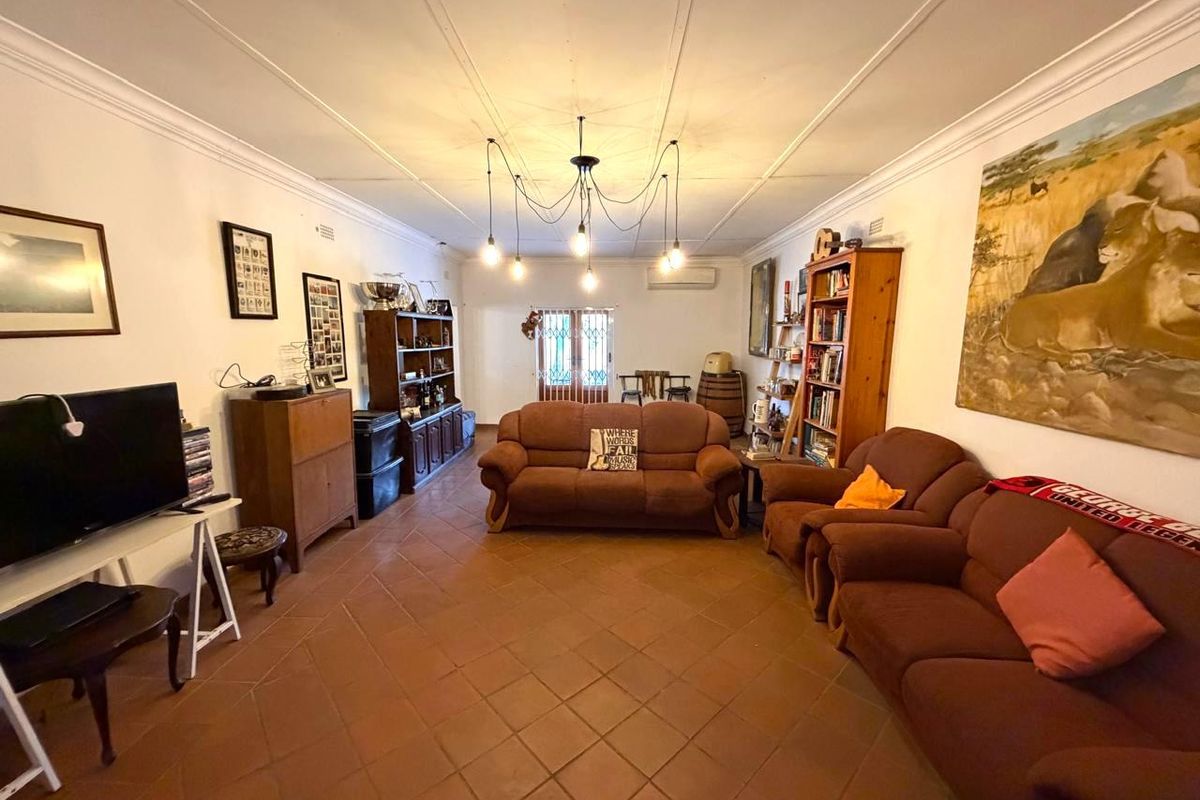 Spacious living room featuring terracotta floor tiles, decorative ceiling detailing, and a wall-mounted split system air conditioner.