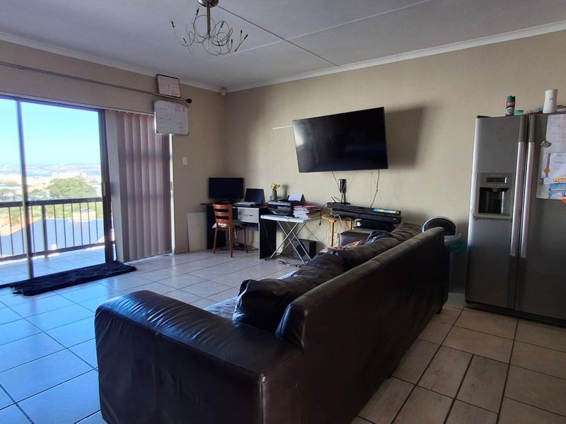 Spacious living area featuring tiled flooring and large sliding glass doors that provide access to a balcony with scenic views.