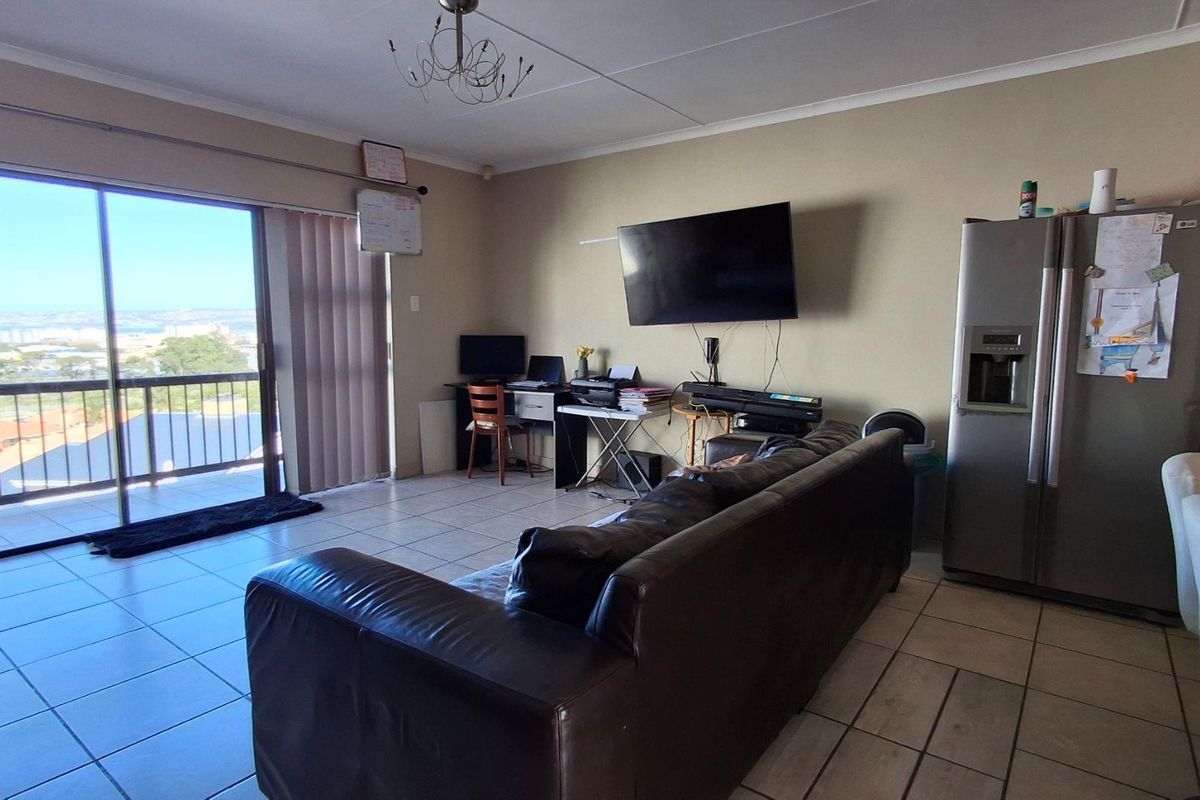 Spacious living area featuring tiled flooring and large sliding glass doors that provide access to a balcony with scenic views.