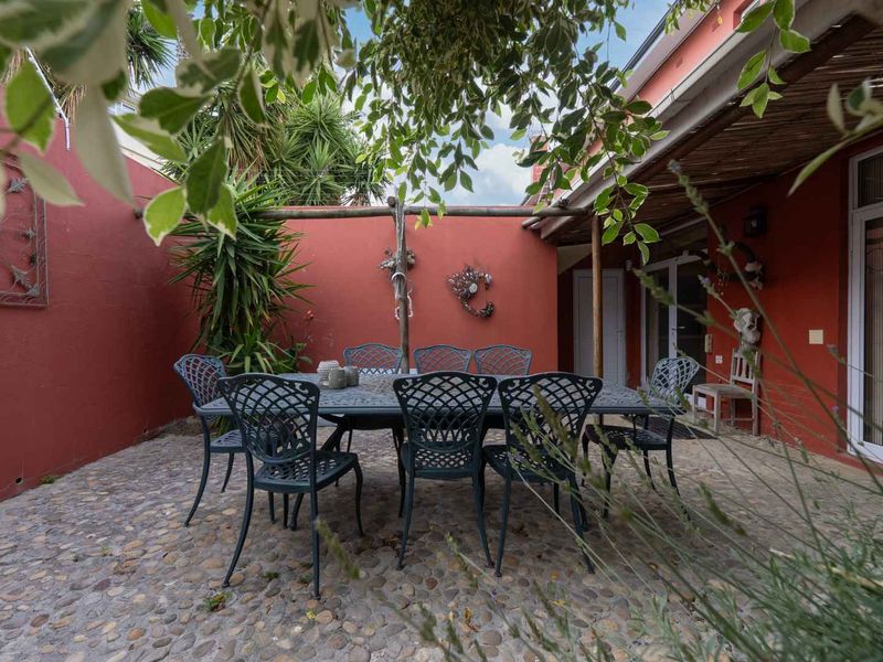 A private outdoor patio area featuring cobblestone paving and a timber pergola, providing a functional space for outdoor dining and relaxation.