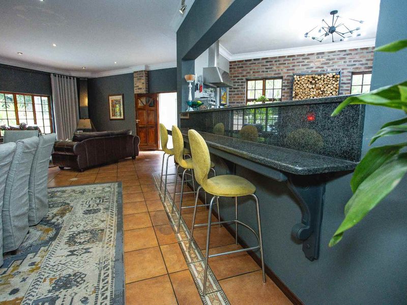 Open plan living and kitchen area featuring a granite breakfast bar, exposed brick accents, and tiled flooring with integrated lighting.