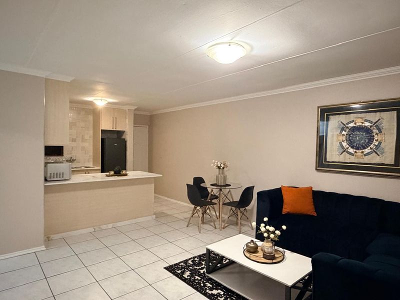 Open plan living and kitchen area featuring tiled flooring, a breakfast bar, and neutral wall finishes.
