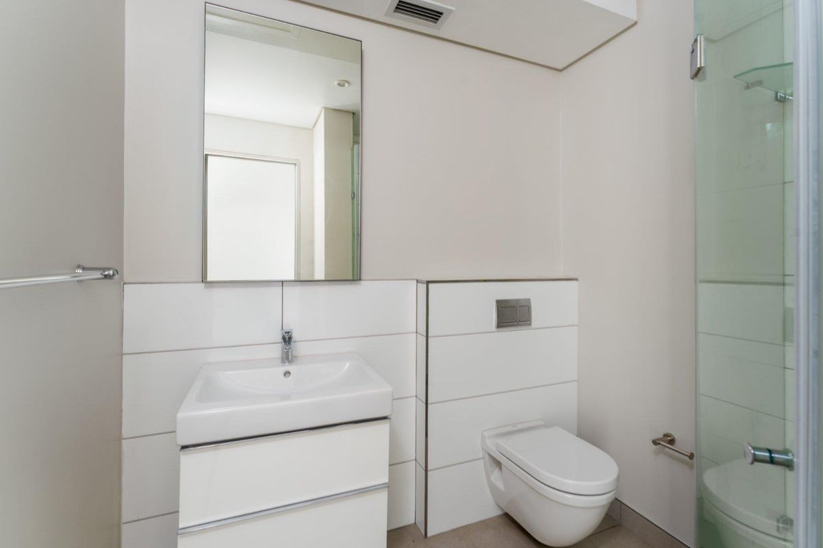 A clean, modern bathroom featuring a wall-mounted vanity, basin, wall-hung toilet with concealed cistern, and a glass shower enclosure.