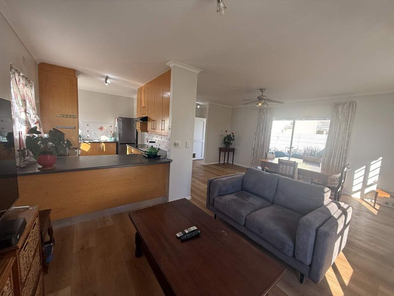 Open-plan living and kitchen area featuring laminate flooring, a breakfast bar, and direct access to the outdoor space through sliding glass doors.
