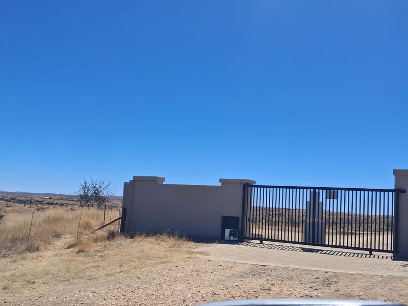 A secure entrance featuring a metal sliding gate and masonry boundary wall, providing access to the small holding property.