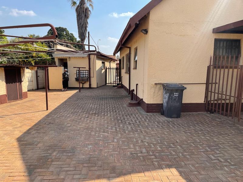 A paved rear courtyard area featuring a secondary structure, security gates, and an external wash basin, providing functional outdoor space.