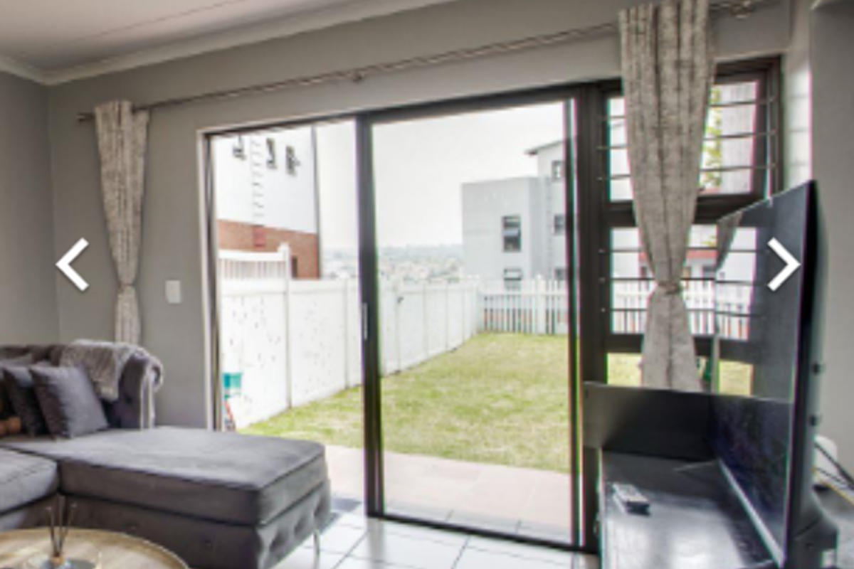 Living room featuring tiled flooring and large sliding glass doors providing direct access to the rear garden area.