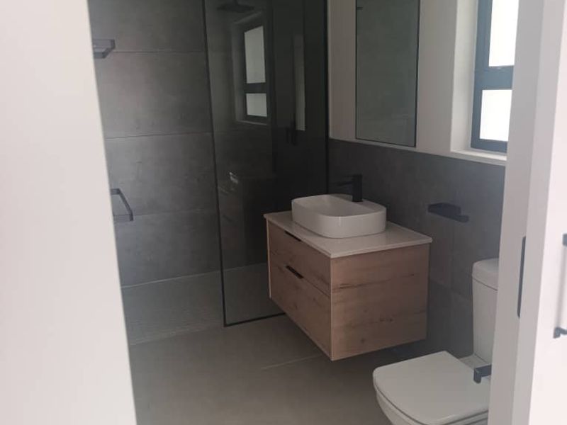Modern bathroom featuring a floating vanity with vessel sink, walk-in shower with glass screen, and contemporary grey tiling.