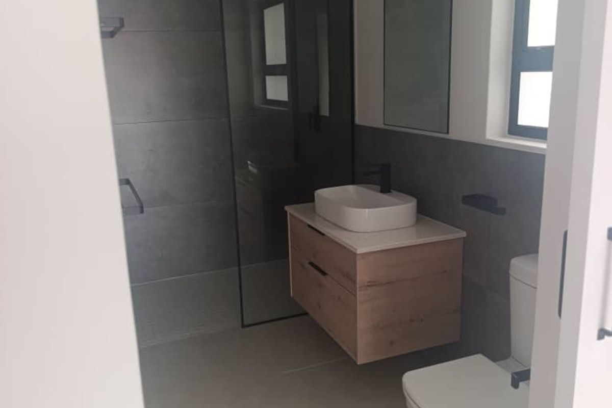 Modern bathroom featuring a floating vanity with vessel sink, walk-in shower with glass screen, and contemporary grey tiling.