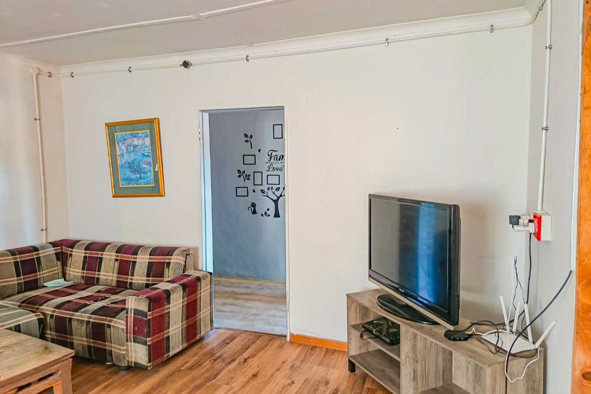 A living room featuring wood-look flooring and exposed surface-mounted electrical conduit along the walls.