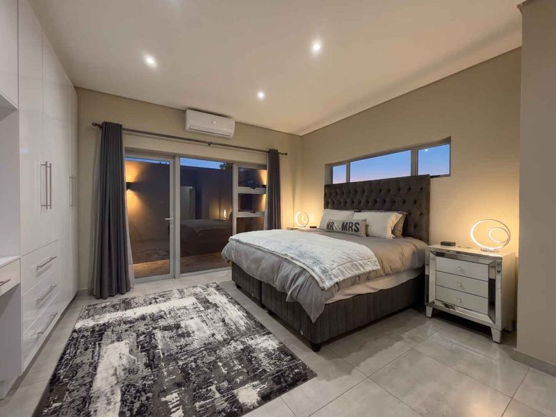 Modern bedroom featuring tiled floors, built-in cupboards, recessed lighting, and a sliding glass door providing access to the exterior.
