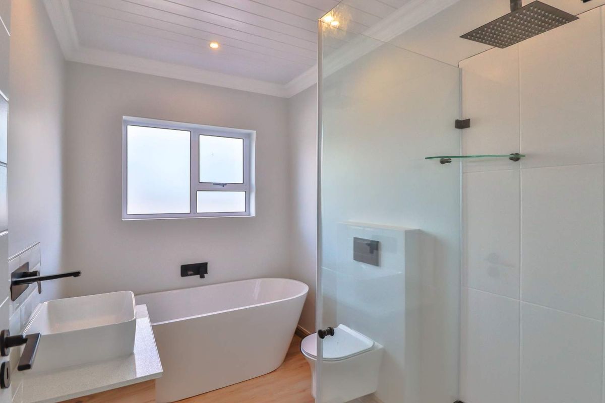 Modern bathroom featuring a freestanding bathtub, a glass-enclosed walk-in shower with a rainfall showerhead, and a contemporary vessel sink.