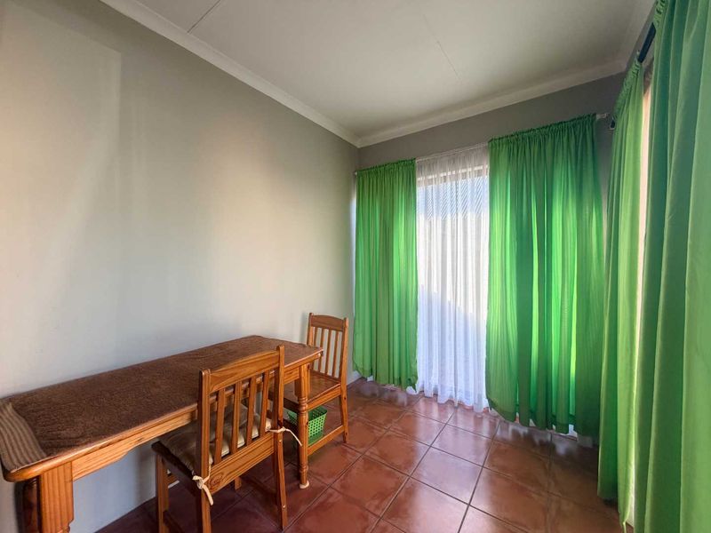 A bedroom featuring tiled flooring and a sliding glass door with curtains, providing access to the exterior.