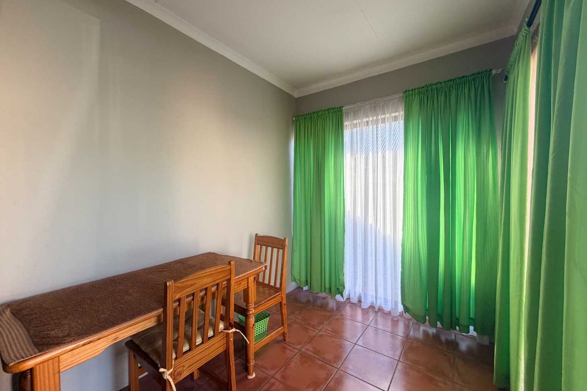 A bedroom featuring tiled flooring and a sliding glass door with curtains, providing access to the exterior.