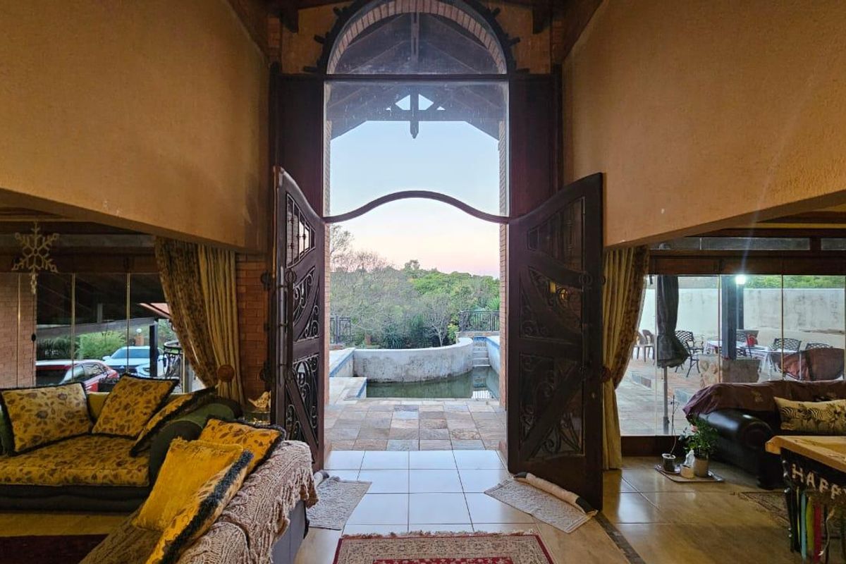 Spacious living area featuring high vaulted ceilings, large arched double doors, and seamless transition to an outdoor patio and pool area.