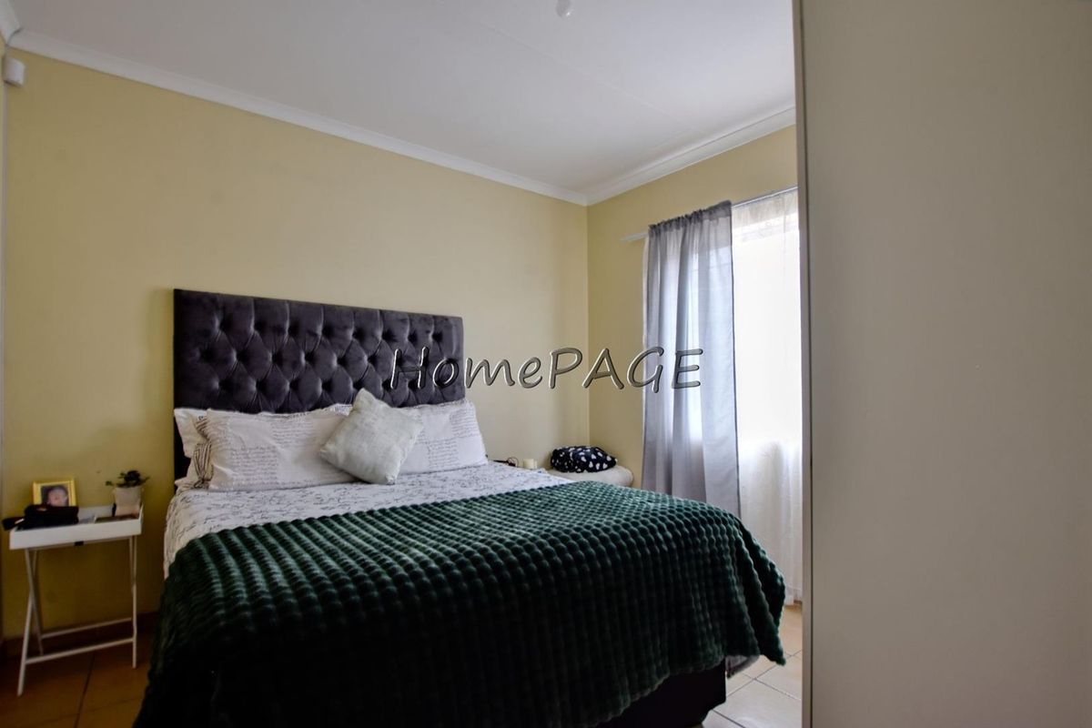 A bedroom featuring tiled flooring and coved ceilings, offering a functional space with natural light.