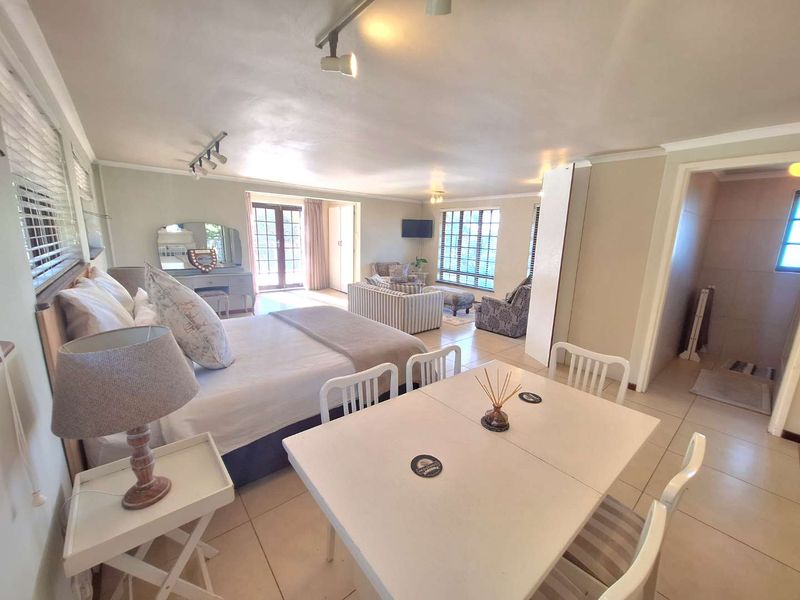 Spacious open-plan living area featuring tiled flooring, track lighting, and direct access to an outdoor space through french doors.