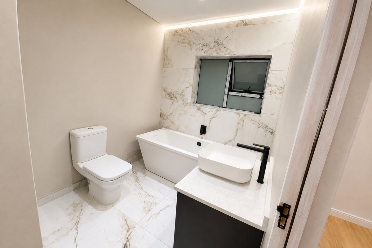 Modern bathroom featuring a freestanding bathtub, vessel sink on a vanity cabinet, and elegant marble-look tiling with contemporary black fixtures.