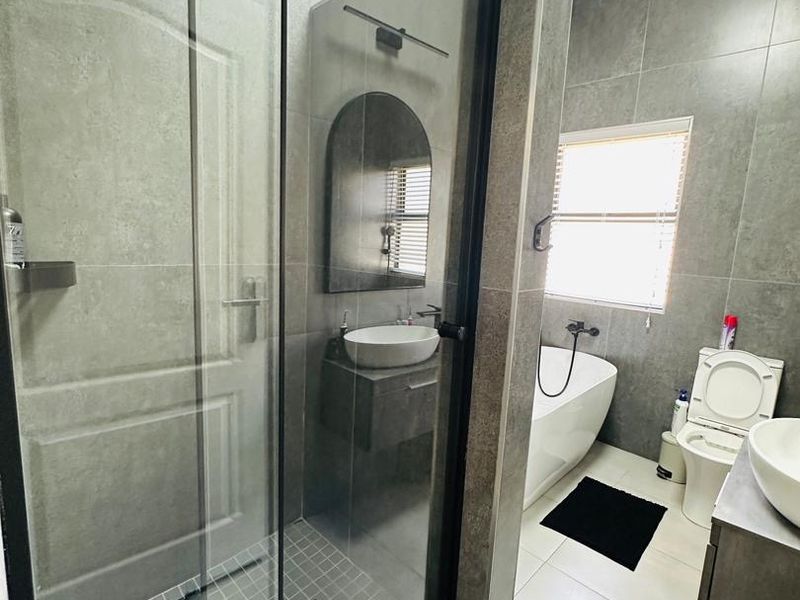 Modern bathroom featuring a walk-in shower with glass enclosure, a freestanding bathtub, wall-mounted toilet, and a vanity with a vessel sink.