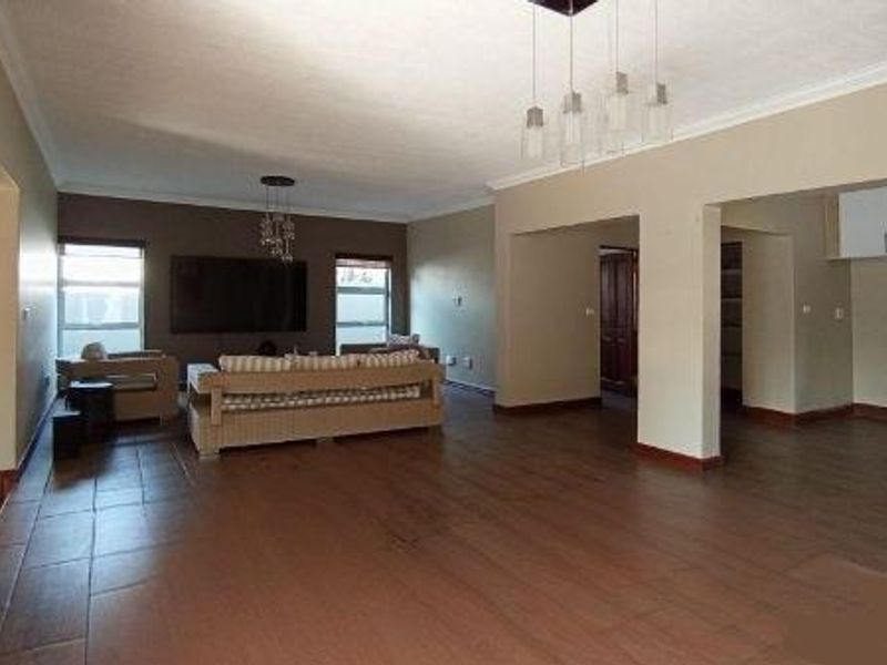 Spacious open-plan living and kitchen area featuring tiled floors, a stone accent wall, and modern pendant lighting, offering a versatile layout for family living.