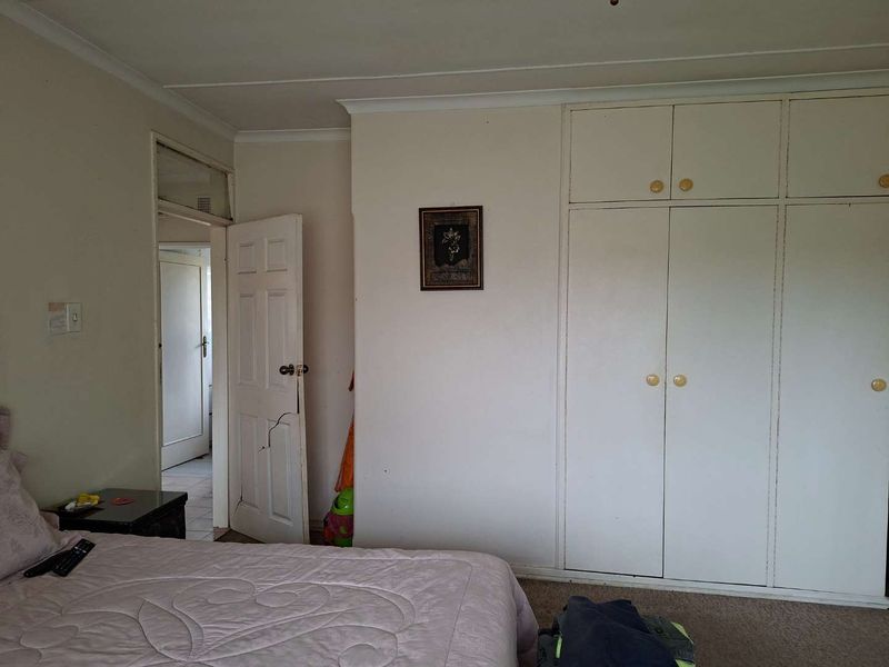 A bedroom featuring built-in cupboards with overhead storage and a standard internal door leading to an adjacent hallway.