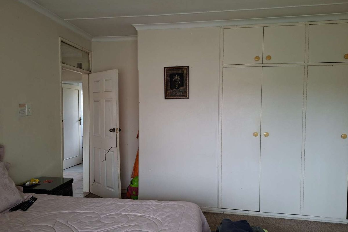 A bedroom featuring built-in cupboards with overhead storage and a standard internal door leading to an adjacent hallway.