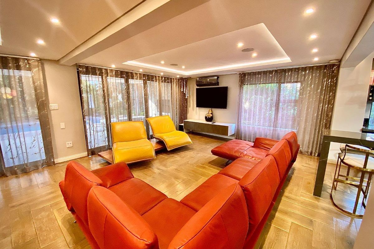 Spacious living room featuring recessed tray ceiling with integrated downlighting, large glass sliding doors, and high-quality timber-look flooring.