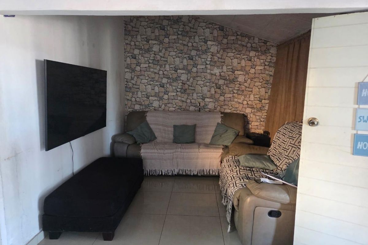 A compact living room featuring tiled flooring and a stone-effect feature wall, providing a cozy and functional space.