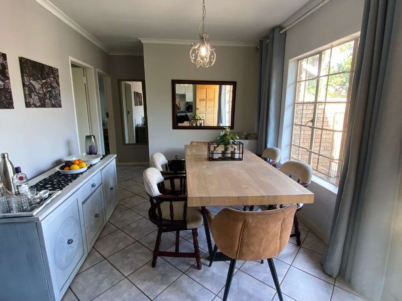A well-lit dining room featuring tiled flooring, a coved ceiling, and a large grid-pattern window providing natural light.