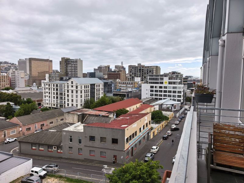 An elevated urban view overlooking the surrounding city buildings and streetscape from a balcony.