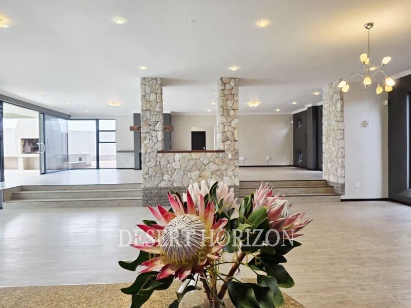 Spacious open-plan living area featuring stone-clad pillars, multi-level flooring, and large sliding glass doors leading to an outdoor patio.