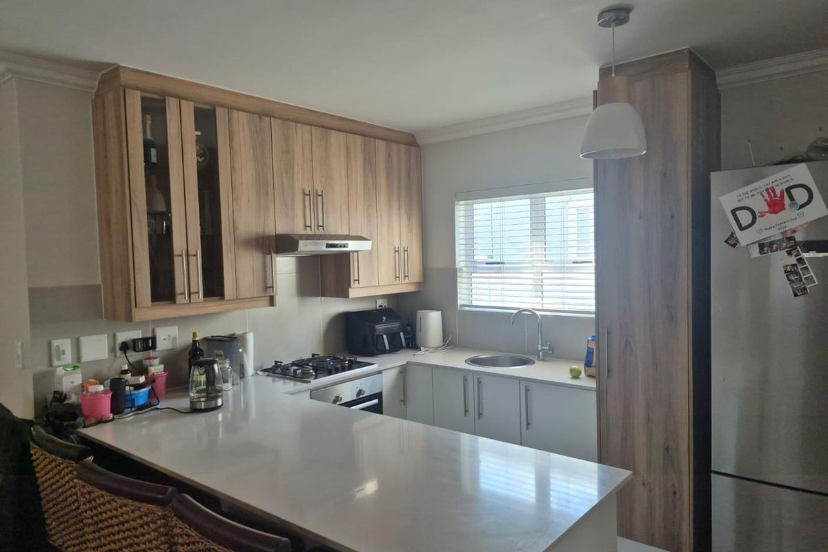 Modern kitchen featuring wood-look cabinetry, stone countertops, a gas hob, integrated extractor, and a functional breakfast bar area.