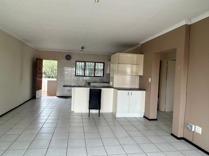 Open plan living and kitchen area featuring tiled flooring, built-in cabinetry, and a breakfast bar, with direct access to an outdoor space.