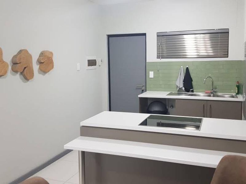 Modern kitchen featuring built-in cabinetry, a sleek hob, stainless steel sink, and a stylish tiled splashback, offering a functional and contemporary cooking space.