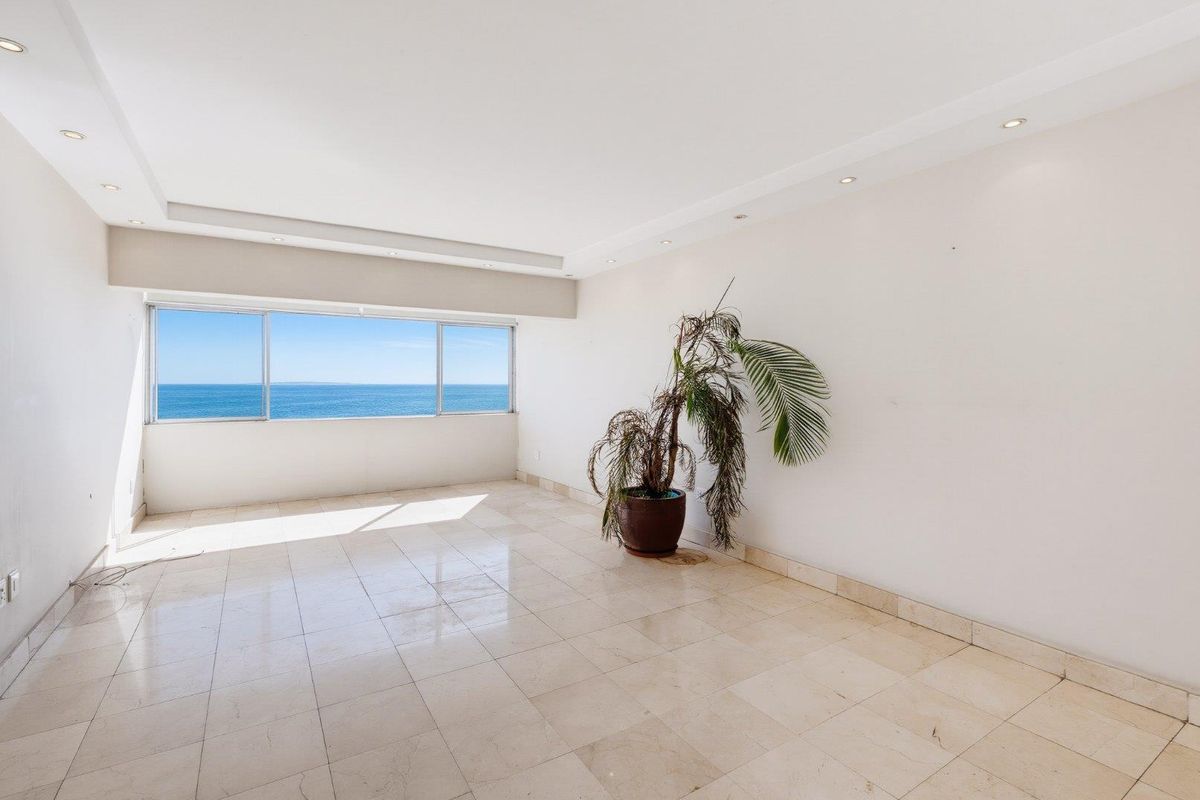Spacious, light-filled living area featuring polished marble flooring, recessed ceiling lighting, and expansive windows offering panoramic ocean views.