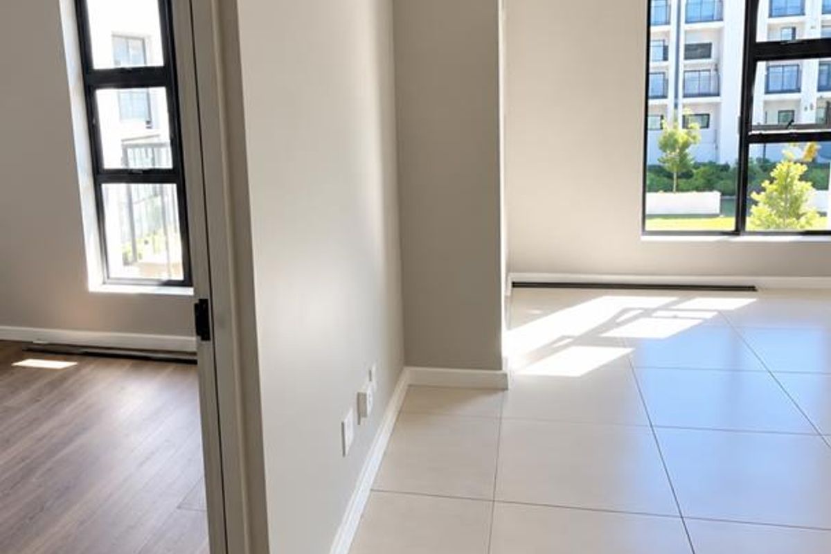 Bright and modern open-plan living area featuring neutral tiled floors, clean finishes, and large windows allowing for ample natural light.