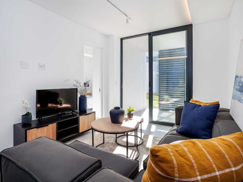 Modern living room featuring tiled floors, recessed lighting, and large sliding glass doors providing access to an outdoor area.