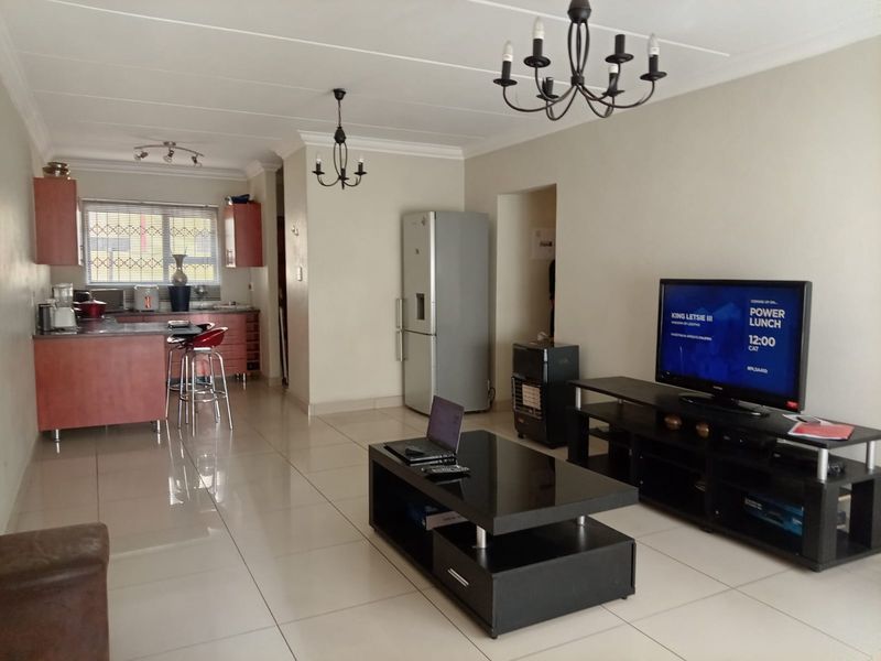 Open plan living area featuring tiled flooring and a functional kitchen with cabinetry and island, creating a versatile space for dining and relaxation.