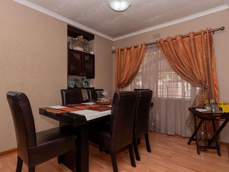 Dining room featuring laminate flooring and a built-in wall niche, with visible ceiling water staining.
