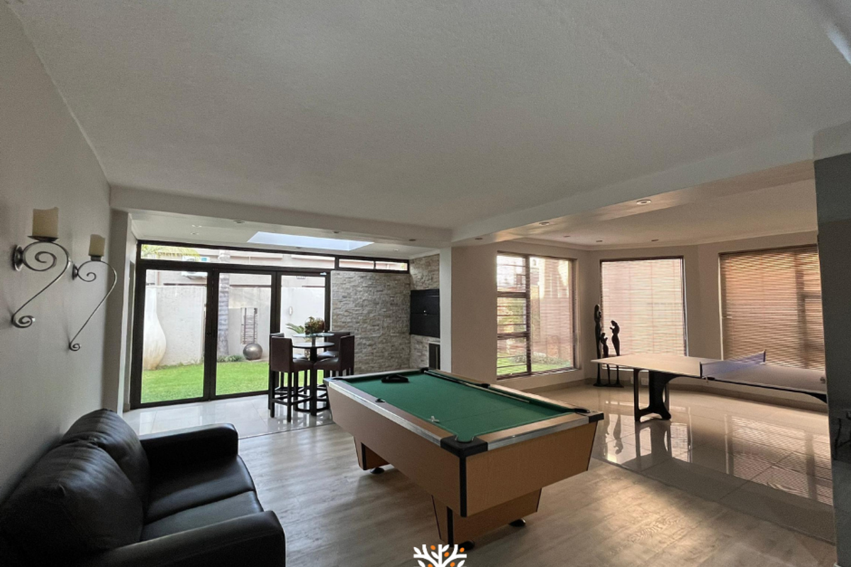 Spacious open-plan living area featuring tiled and laminate flooring, a stone feature wall with a built-in fireplace, and large sliding doors leading to the garden.