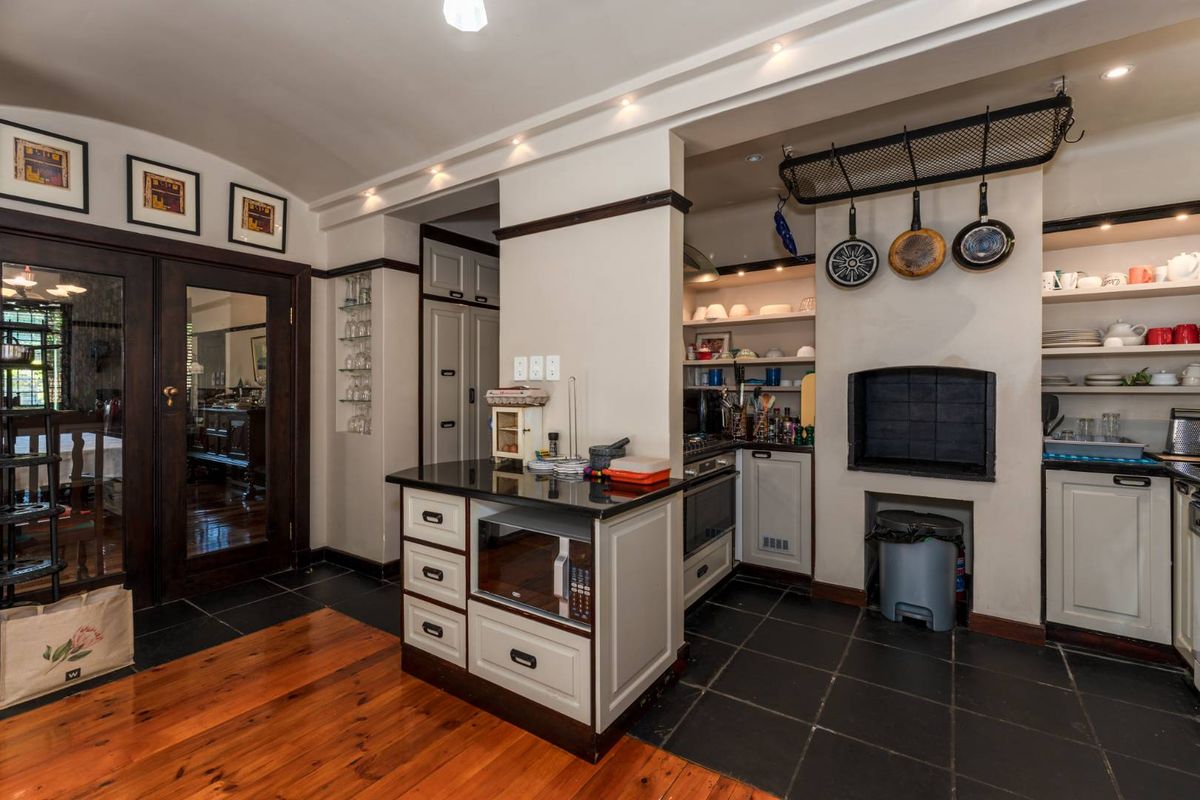 A well-appointed kitchen featuring a central island, built-in oven, integrated shelving, and a dedicated indoor braai area with dark tiled flooring.