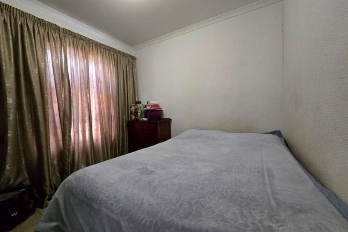 A bedroom featuring tiled flooring and cove cornicing, currently requiring cosmetic updates to the wall finishes.