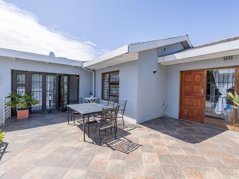 Spacious outdoor patio area featuring tiled flooring, direct access to the home via timber and glass doors, and secure window fixtures.