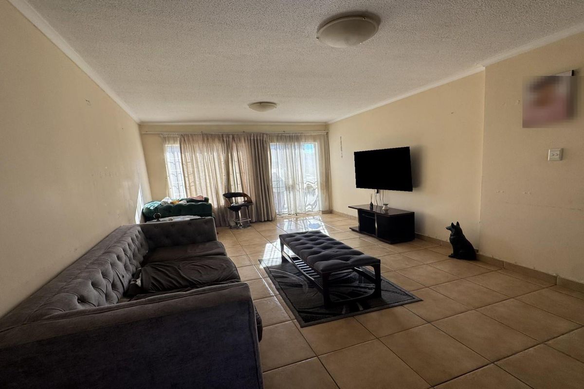 Spacious living room featuring neutral tiled flooring and large sliding glass doors that provide natural light and access to the outdoor area.