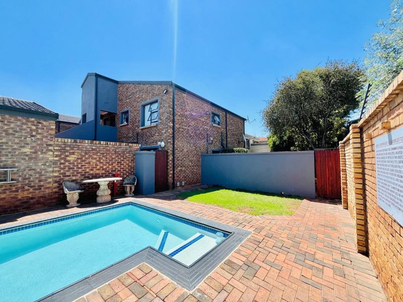 Private outdoor pool area featuring brick paving, a small lawn, and secure boundary walls, providing a functional space for relaxation and recreation.