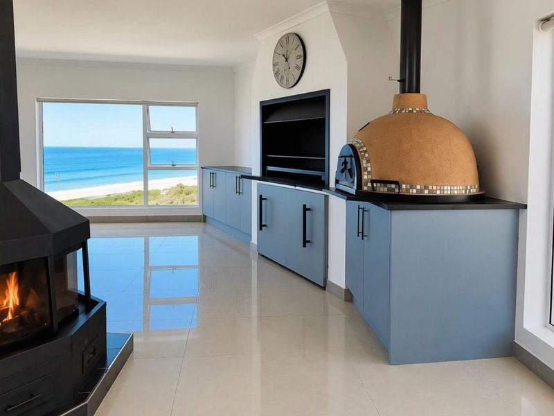 Spacious living area featuring a built-in fireplace, indoor braai, and pizza oven, with large windows offering stunning ocean views.