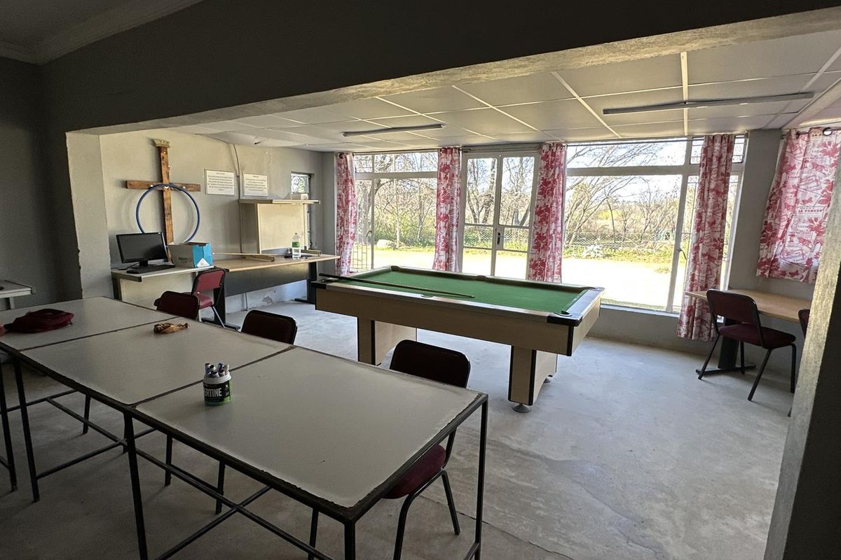 A spacious multi-purpose room featuring large glass sliding doors, concrete flooring, and a suspended ceiling, offering potential for a versatile living or entertainment area.
