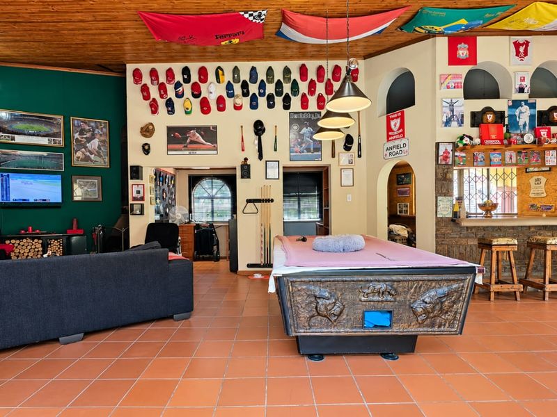 Spacious living and entertainment area featuring a timber-clad ceiling, terracotta flooring, and a built-in bar with arched architectural wall niches.